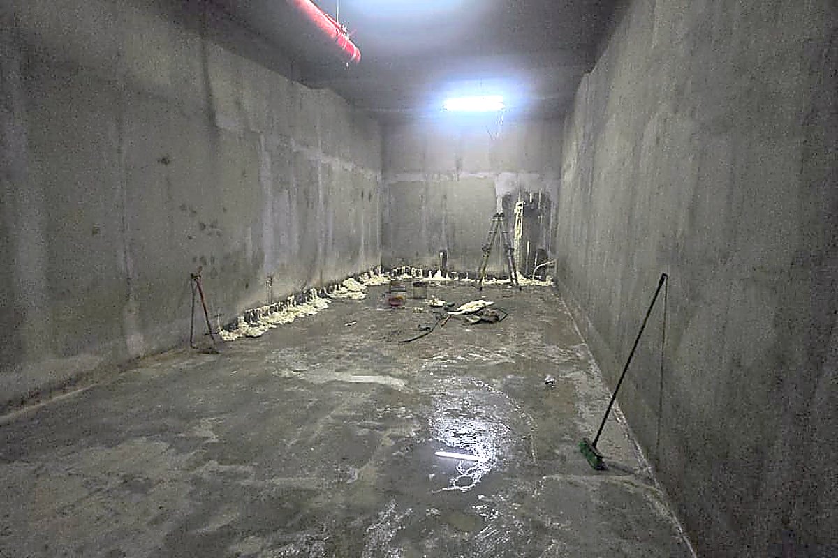 Recinto subterráneo de hormigón con agua acumulada en el piso y puertos de inyección instalados en el encuentro entre muro y losa